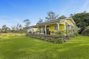 A yellow house with a porch, surrounded by a well-maintained lawn and trees.