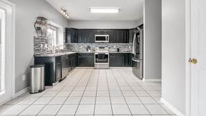 Una cocina moderna con armarios oscuros, una isla central, un refrigerador de acero inoxidable y un microondas.