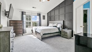 Un dormitorio con cama, cómoda, mesita de noche y ventilador de techo.