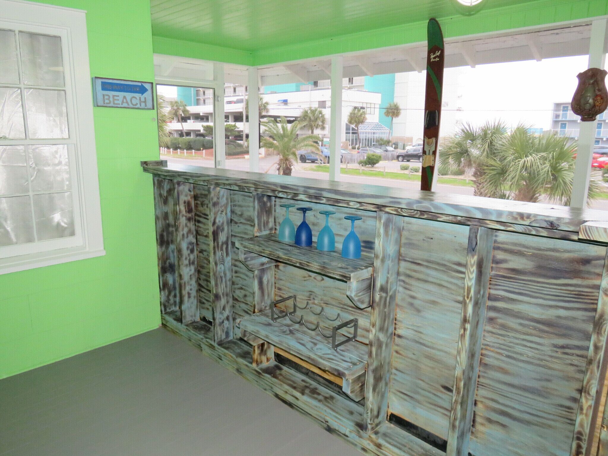 Un espace bar décoré sur le thème de la plage, avec un panneau indiquant la direction à suivre pour s’y rendre.