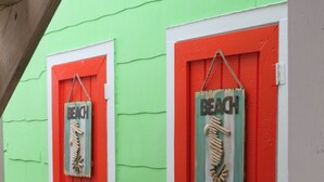 Two red doors with 'BEACH' signs and wooden sculptures of beach elements. - Location Location Location! Classic Beach Cottage less than 1-min walk to beach! (Murrells Inlet)