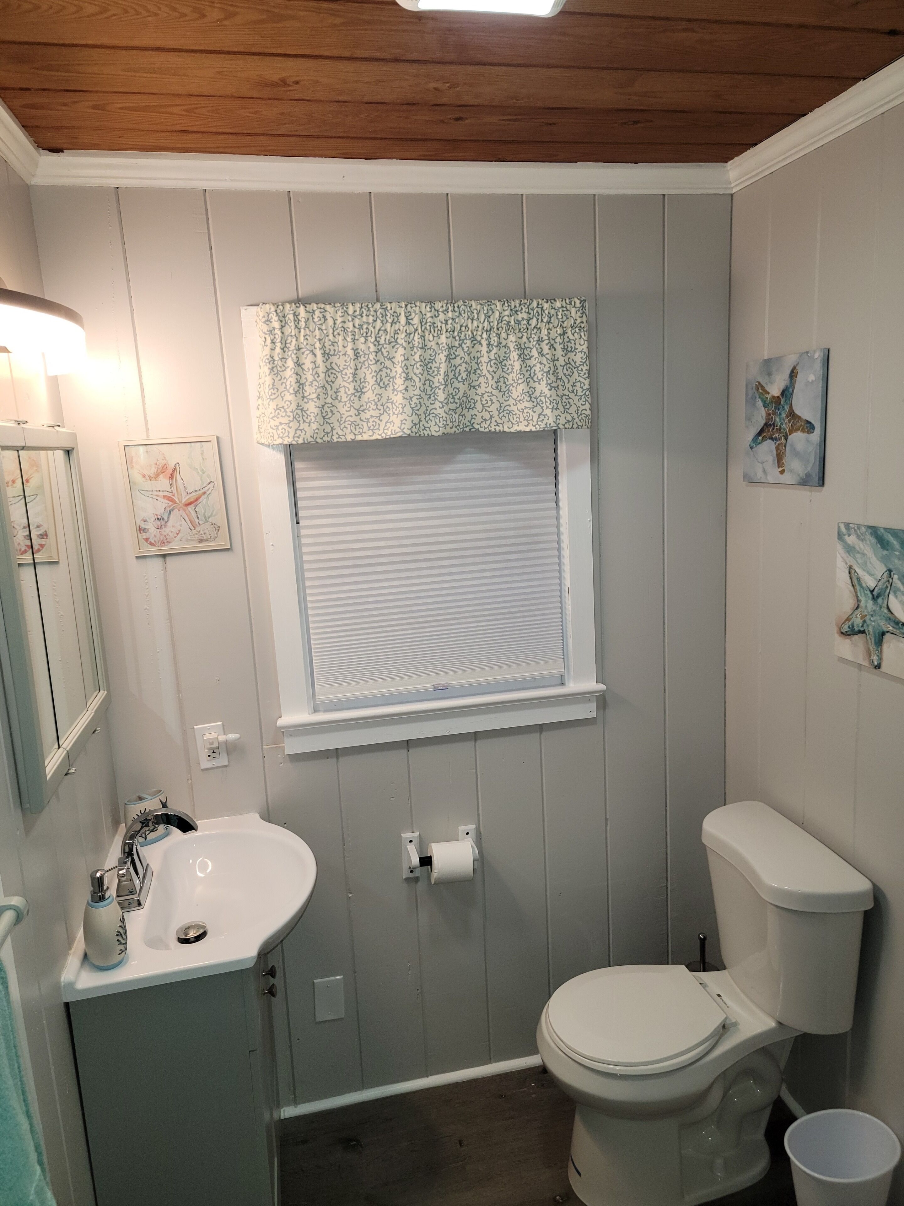 A bathroom with a toilet, sink, and window with blinds.
