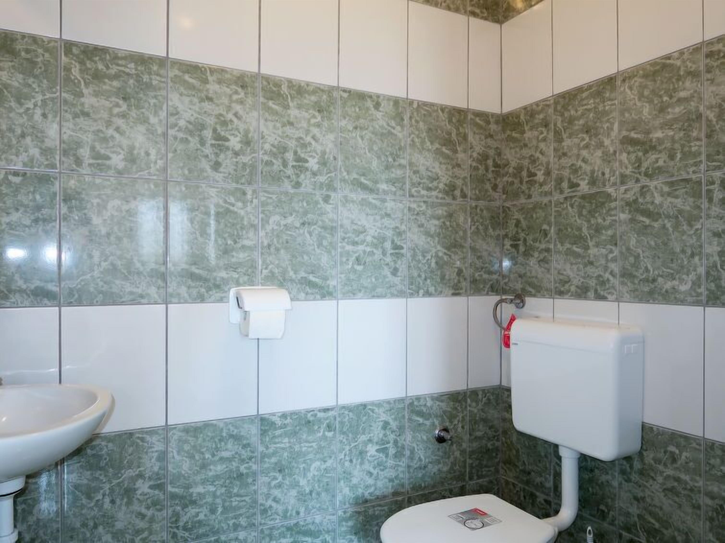 Et badeværelse med toilet, vask og papirhåndklædedispenser.