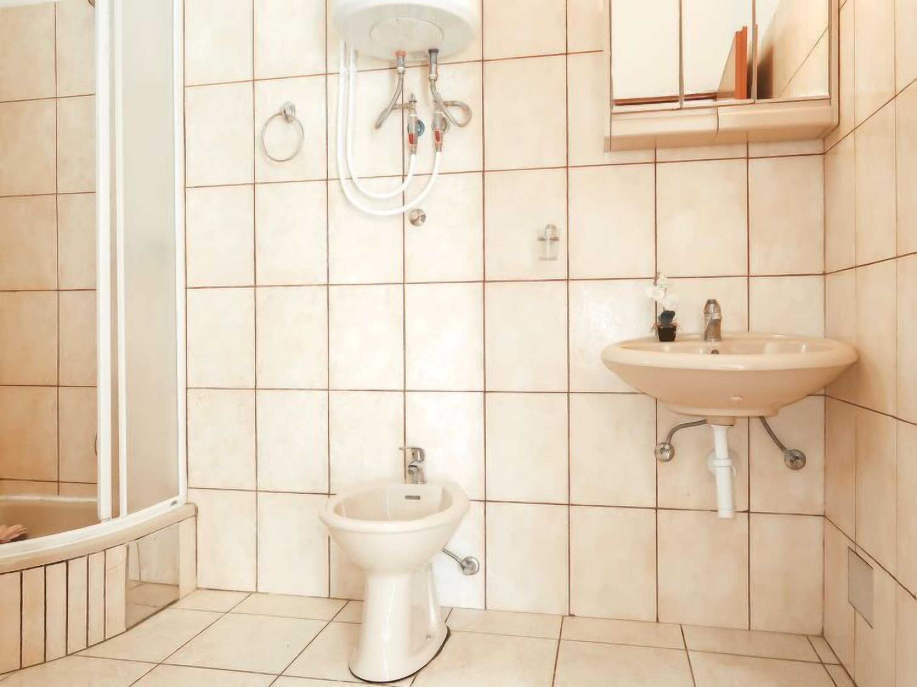 Un baño con inodoro, bidé, lavamanos y ducha.