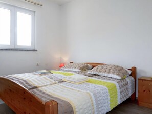 Une chambre à coucher avec un lit en bois, une table de chevet, une lampe et une fenêtre.