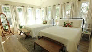 Un dormitorio con dos camas, un banco de madera, una mesita y un espejo.