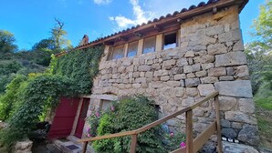 A stone building with a red door, a wooden staircase, and a red railing. - Superb loft gîte / bed and breakfast:<br>La grange d ArtDèche (Saint-Martin-de-Valamas)