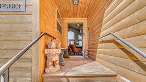A wooden staircase leading to a room with a 'Welcome' sign and a teddy bear decoration.