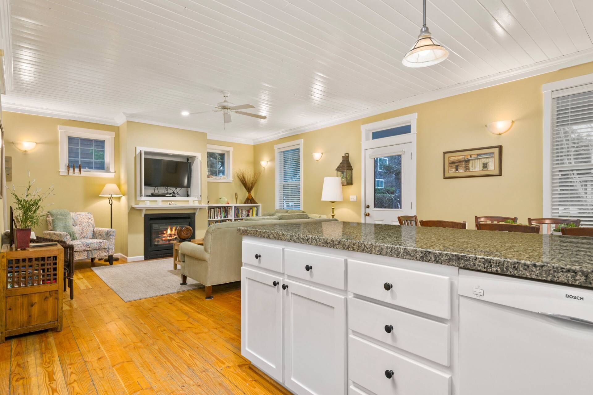 A kitchen with white cabinets, a granite countertop, and a Bosch dishwasher.