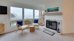 Un salón amplio con ventanas grandes, una chimenea y muebles de mimbre.