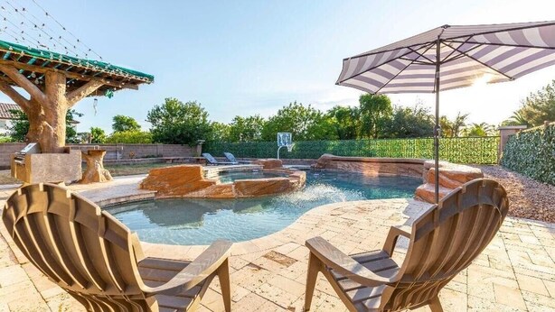 Ett utomhusområde med en pool, ett bubbelbad, solstolar och en pergola.