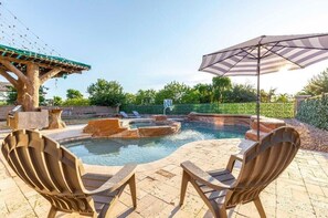 Ein Außenpoolbereich mit Whirlpool, Liegestühlen und einer Pergola.