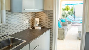 A modern kitchen with a built-in sink, a coffee machine, and a view of a patio with outdoor furniture. - Nice villa with private pool and pool house (Montaigu de Quercy)