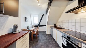 Een moderne keuken met een houten aanrechtblad, een inbouwoven en een zwarte achterwand.