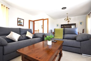 A living room with a dark-colored sofa, a wooden coffee table, and a bookshelf.