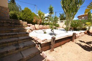 A stone staircase leading to a building, surrounded by desert vegetation and a clear blue sky.
