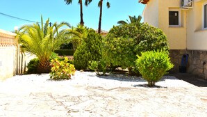 A courtyard with palm trees, a stone floor, and a building with a stone wall and a window. - Villa Cucarres with sea and mountain views, Wi-Fi, air conditioning, and garden (Calpe)