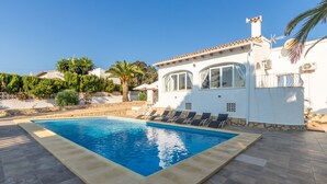 A swimming pool with lounge chairs, a white building with arched windows, and a clear blue sky. - Villa Rosa with mountain views, pool, Wi-Fi, air conditioning, terrace and garden (Benissa)