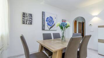 A dining area with a wooden table, six chairs, and two wall-mounted paintings.