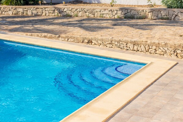 A swimming pool with clear blue water, surrounded by a stone wall and a tiled deck. - Villa Rosa with mountain views, pool, Wi-Fi, air conditioning, terrace and garden (Benissa)