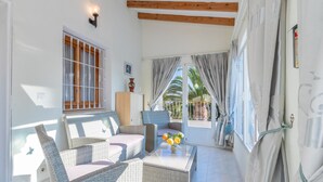 A bright room with wicker furniture, a glass coffee table, and a view of palm trees. - Villa Rosa with mountain views, pool, Wi-Fi, air conditioning, terrace and garden (Benissa)