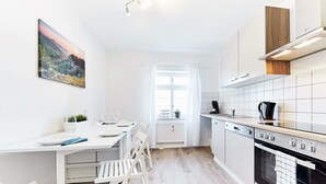 A modern kitchen with white cabinetry, a dining table with chairs, and a view of a mountainous landscape through a window. - Large, beautiful vacation apartment with 2 bedrooms (Ettenheim)