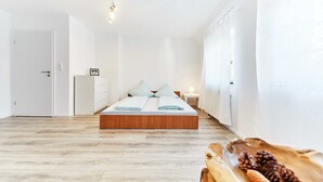 A bedroom with a wooden platform bed, white walls, and a wooden floor. - Large, beautiful vacation apartment with 2 bedrooms (Ettenheim)