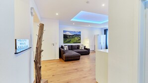 Ein modernes Wohnzimmer mit Holzboden, einem braunen Ecksofa und einem Landschaftsbild an der Wand.