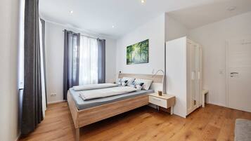 A modern bedroom with a wooden bed, a bedside table, a wardrobe, and a window with curtains.