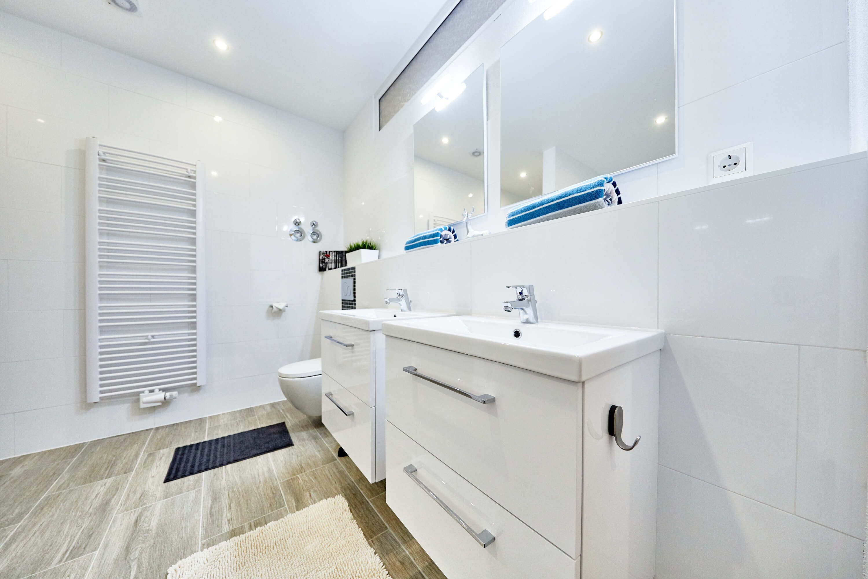 Un bagno moderno con mobili bianchi, uno specchio grande e un water.