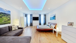 Ein modernes Schlafzimmer mit einem Bett, einer Couch, einem Fernseher und einem Gemälde.