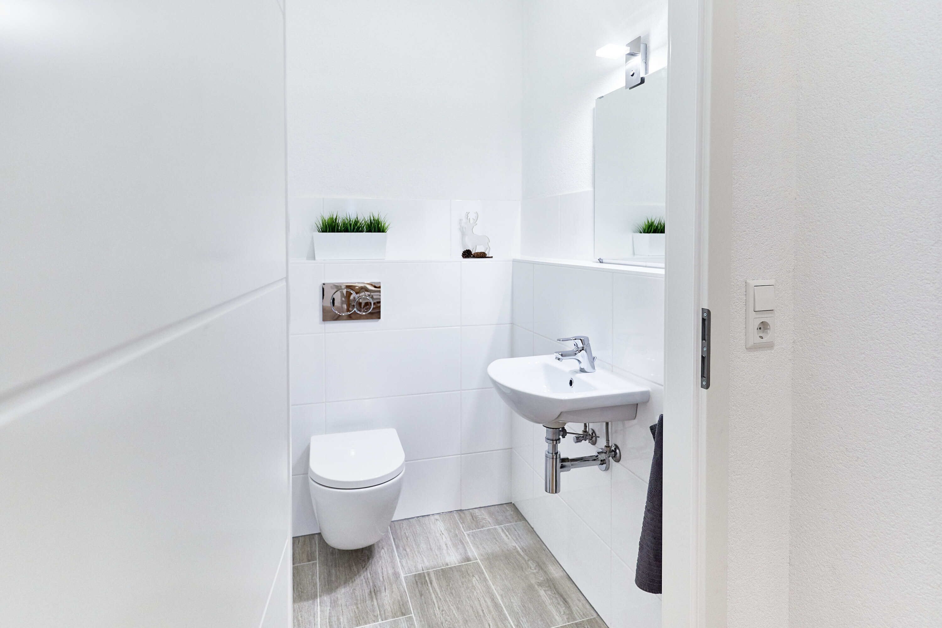 Een moderne badkamer met een wit toilet, een wastafel en een spiegel.