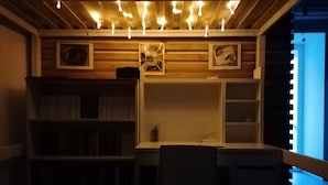 Une pièce faiblement éclairée, avec un bureau, une chaise et des étagères.