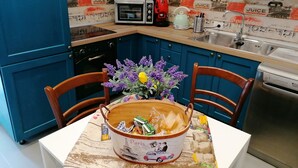 Une cuisine avec des meubles de rangement bleus, un four à micro-ondes, une bouilloire et un évier.