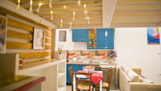 Une cuisine chaleureuse avec des poutres en bois, des armoires bleues et un coin repas comprenant une table et des chaises.