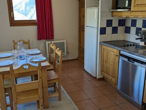 Uma cozinha com armários de madeira, lava-louças de aço inoxidável, micro-ondas e painel de azulejos.