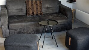 A modern living room with a grey sofa, a small round table, and two ottomans.