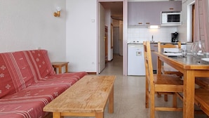 Un espacio habitable compacto con kitchenette, comedor y sofá.