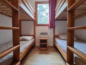 Two guests can sleep comfortably in this compact room with two bunk beds and a nightstand.