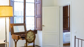 Un dormitorio con cama, escritorio, silla, lámpara y ventana con persianas de madera.