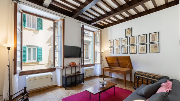 Una sala de estar con techo de madera, un sofá, una mesa de centro y una alfombra roja.