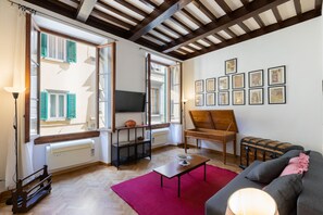 Ein Wohnzimmer mit Holzboden, einer Couch, einem Couchtisch und einem roten Teppich.