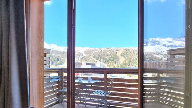 A balcony with a view of a snowy mountain range and a town below.