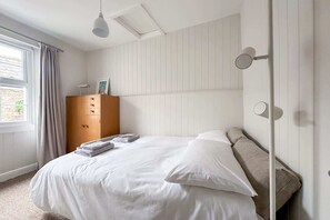 A bedroom with a bed, a wardrobe, a window with curtains, and a ceiling light fixture. - Beautiful House in Bideford on Peaceful Street (Bideford)