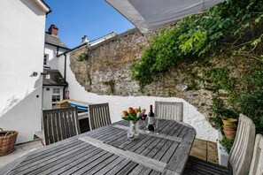 A patio with a table, chairs, and a wine bottle.