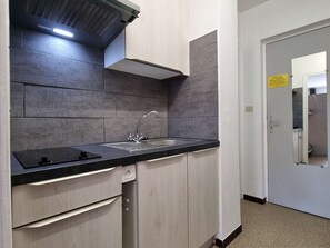 Uma cozinha moderna com azulejos cinzentos, bancada preta e eletrodomésticos de aço inoxidável.