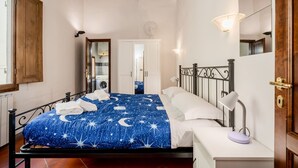 Un dormitorio con cama, mesita de noche, lámpara y espejo.