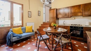 Una cocina acogedora con armarios de madera, una mesa de comedor con sillas y un sofá con cojines amarillos.