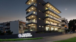 A multi-story building with balconies, illuminated windows, and a sign for Light Blue Luxury Apartments. - Light Blue Luxury Rooms (Nea Propontida)