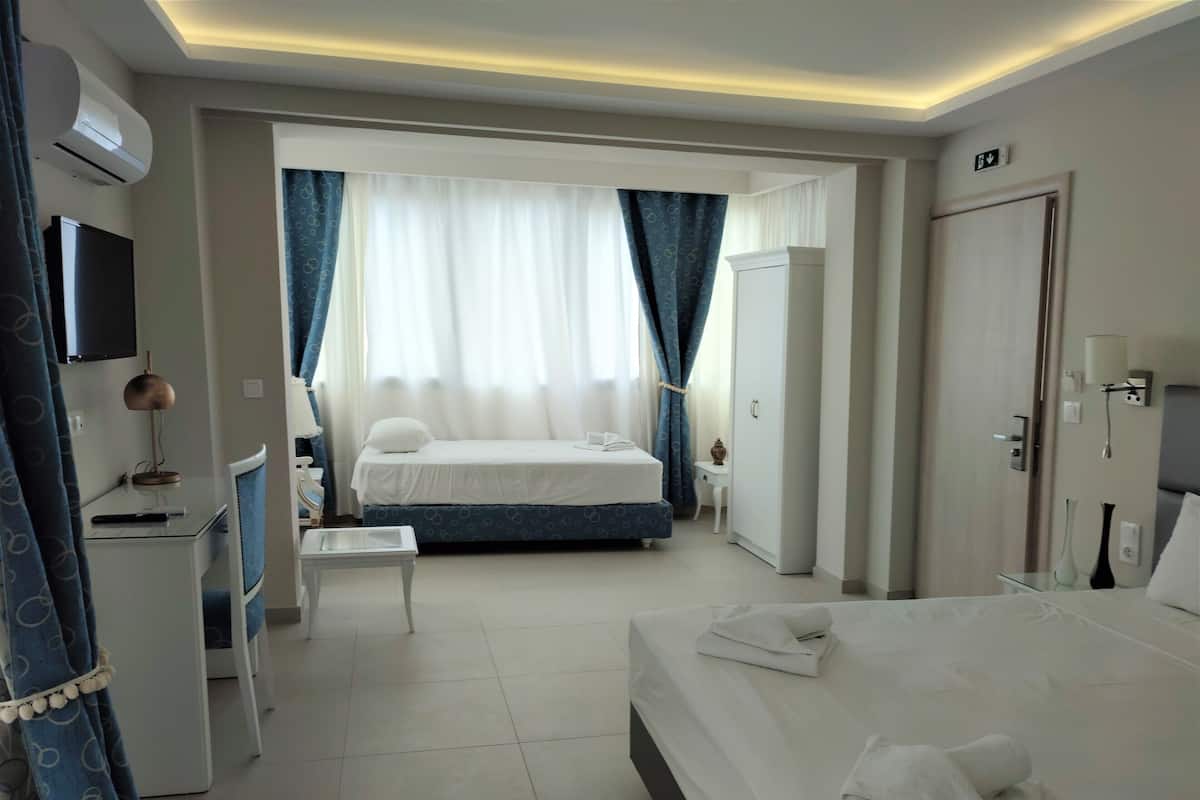 A hotel room with a bed, a desk, a chair, a wardrobe, and a television.